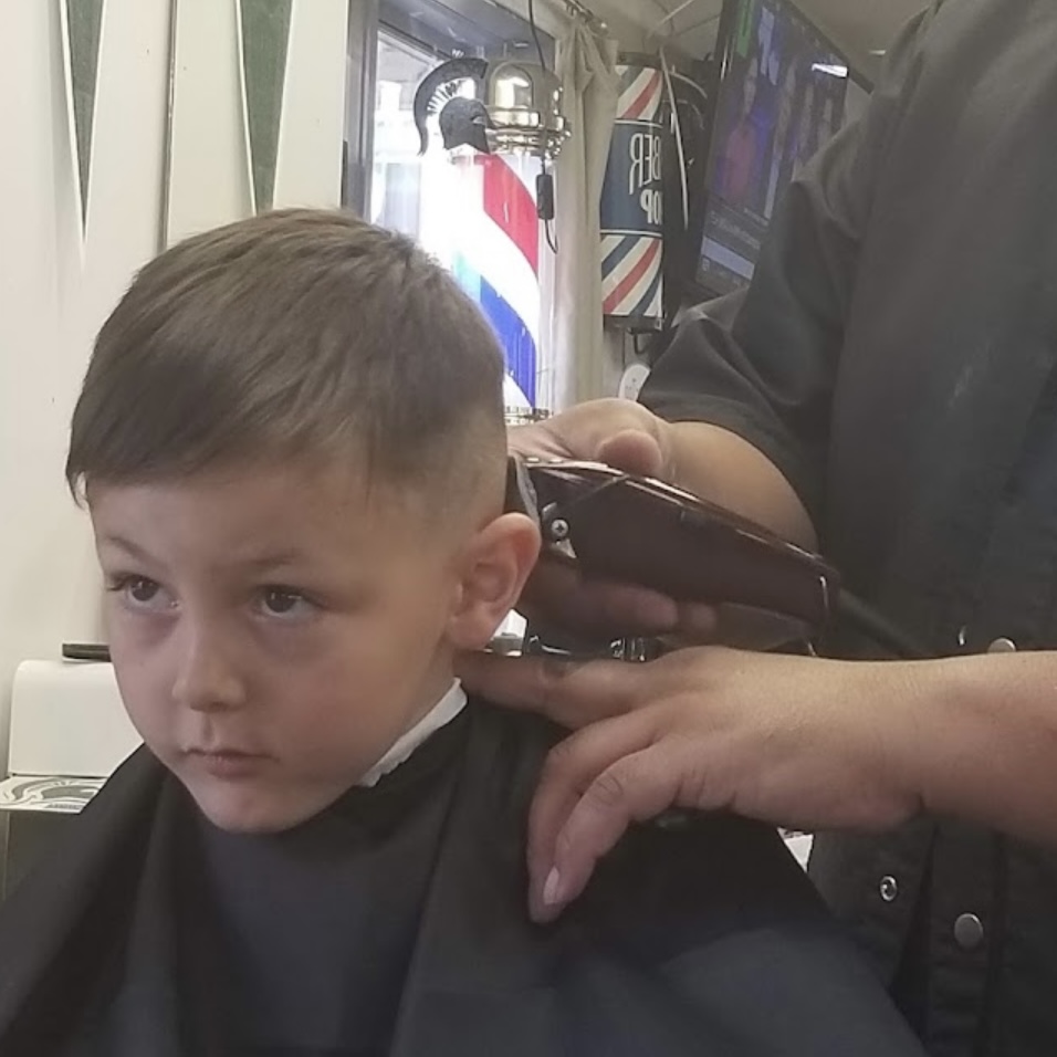 Barber trimming a young boy's haircut